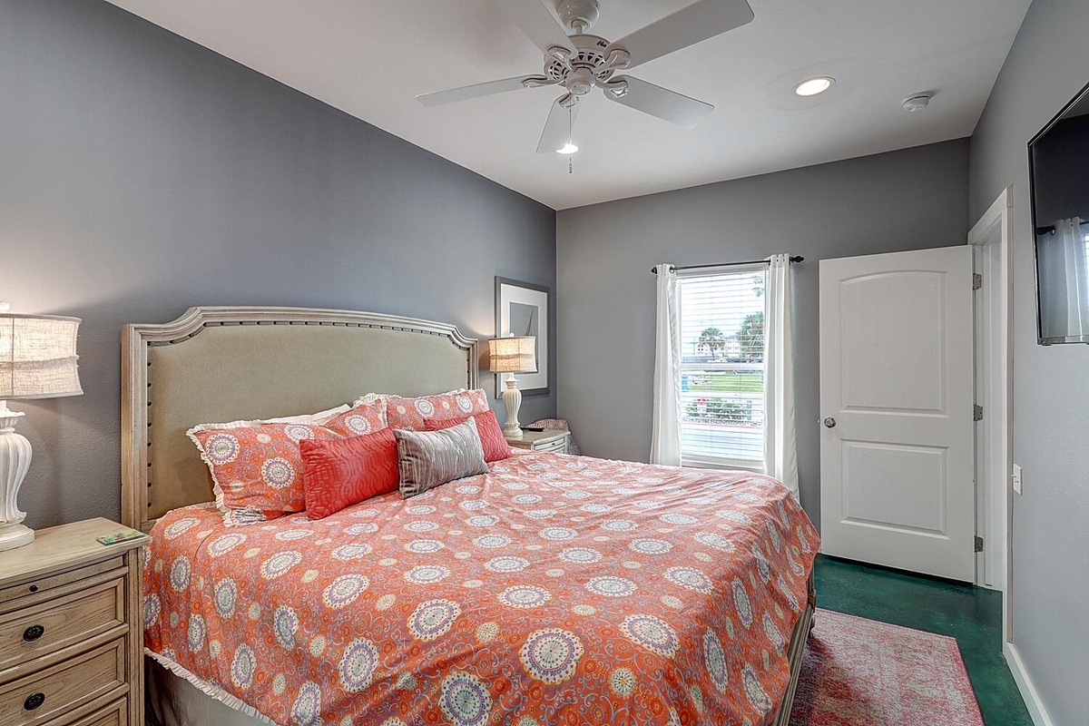 Sink into comfort in your stylish bedroom featuring a plush king bed with vibrant coral linens and elegant furnishings.