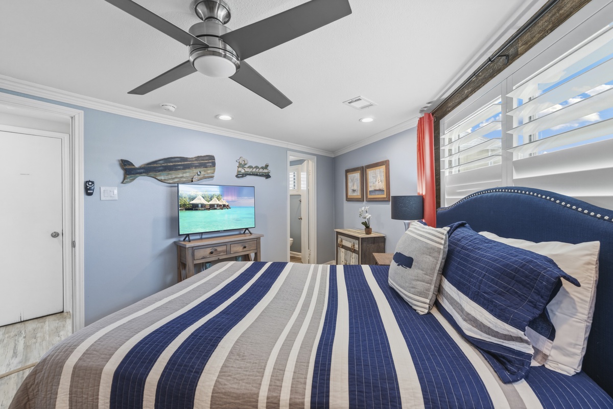 Unwind in your coastal-themed bedroom with nautical décor, ceiling fan comfort, and tropical views on the TV for ultimate relaxation.
