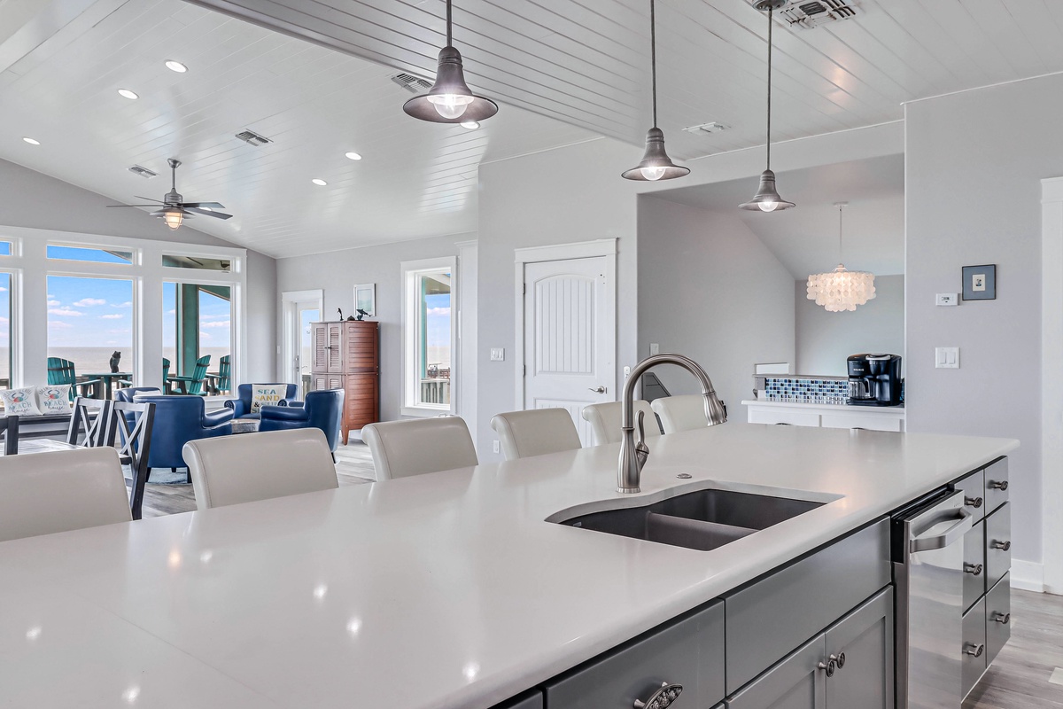 Your modern kitchen island awaits with sleek countertops and coastal charm flowing into the bright dining space beyond.