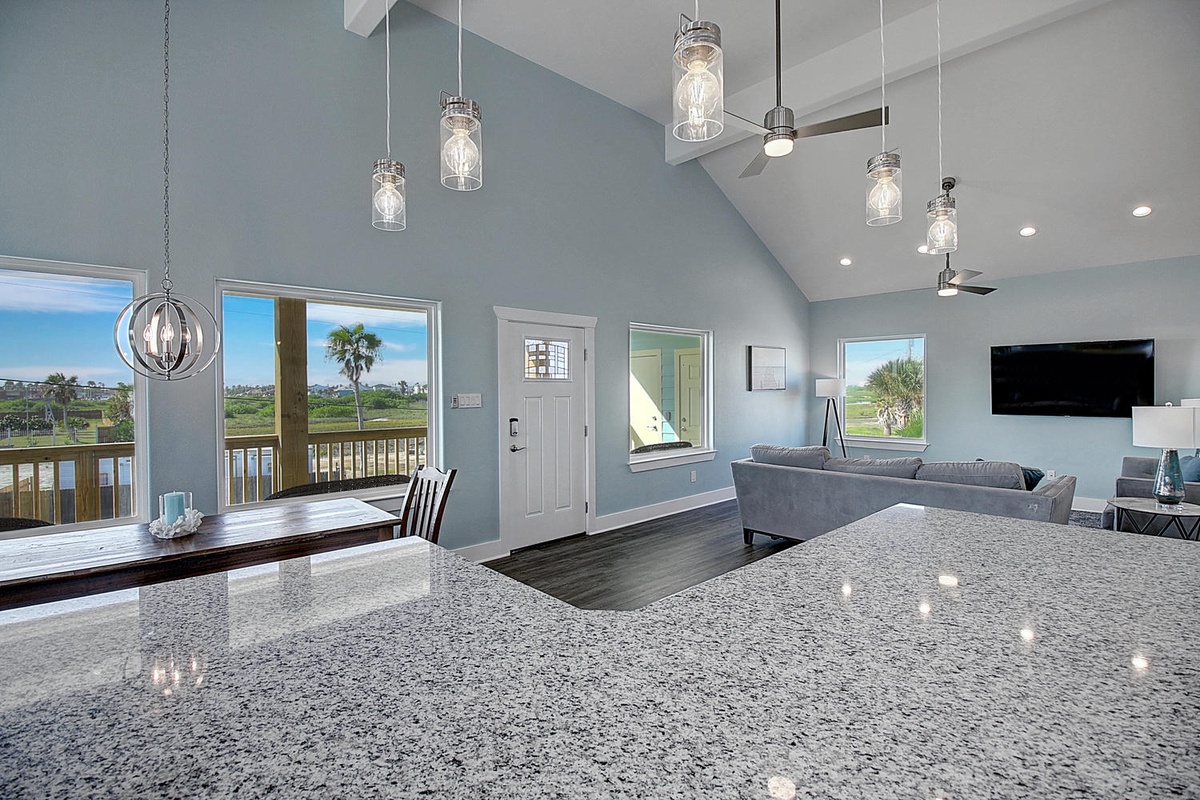 Your open-concept living space features granite counters, pendant lighting, and soaring ceilings that flow seamlessly to your private balcony overlooking coastal views.