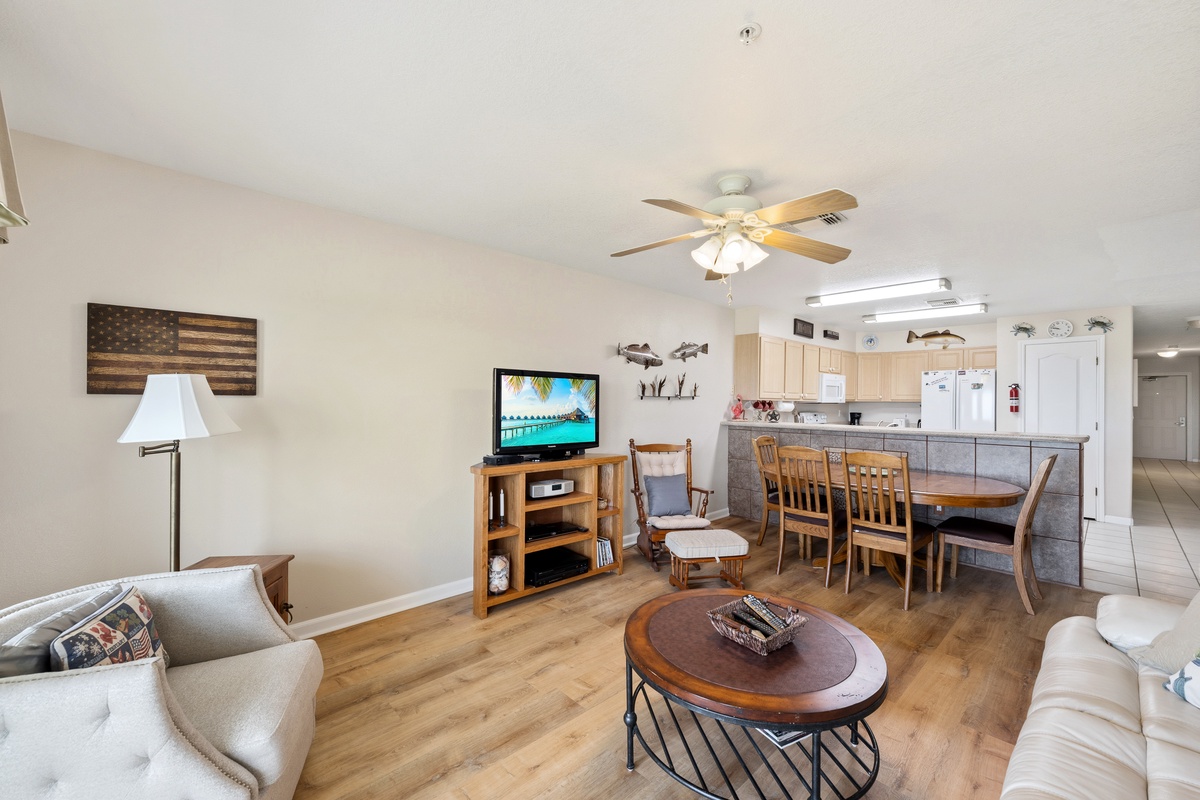 Step into your welcoming open-concept living space where coastal charm meets comfort. Gather around the cozy seating area, share meals at the dining table, and enjoy the easy flow between living and kitchen spaces.