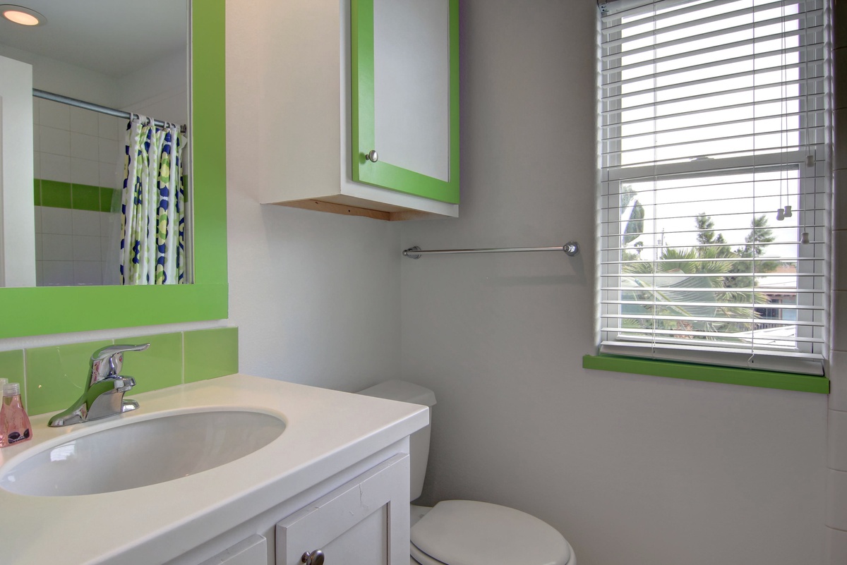 Your bright bathroom features cheerful green accents, modern fixtures, and natural light that creates a refreshing start to your day.