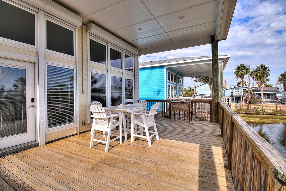 Enjoy morning coffee on your private waterfront deck, where white dining chairs await peaceful moments overlooking the canal and colorful coastal neighborhood.