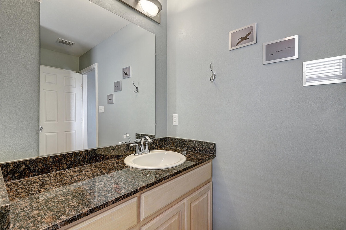 Your private bathroom features elegant granite countertops and coastal artwork, creating a serene space for your morning routine.