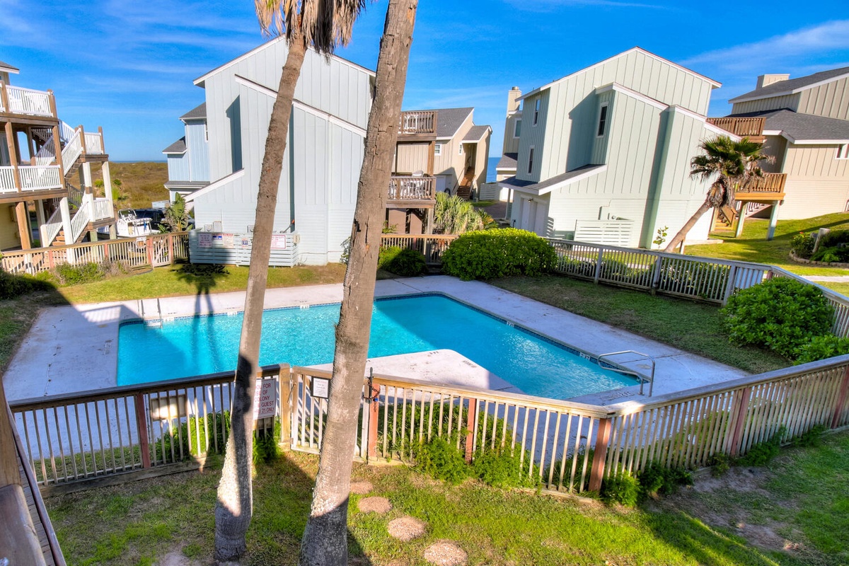 Beachside vacation homes surround a crystal-clear community pool, perfect for cooling off after sunny beach days.