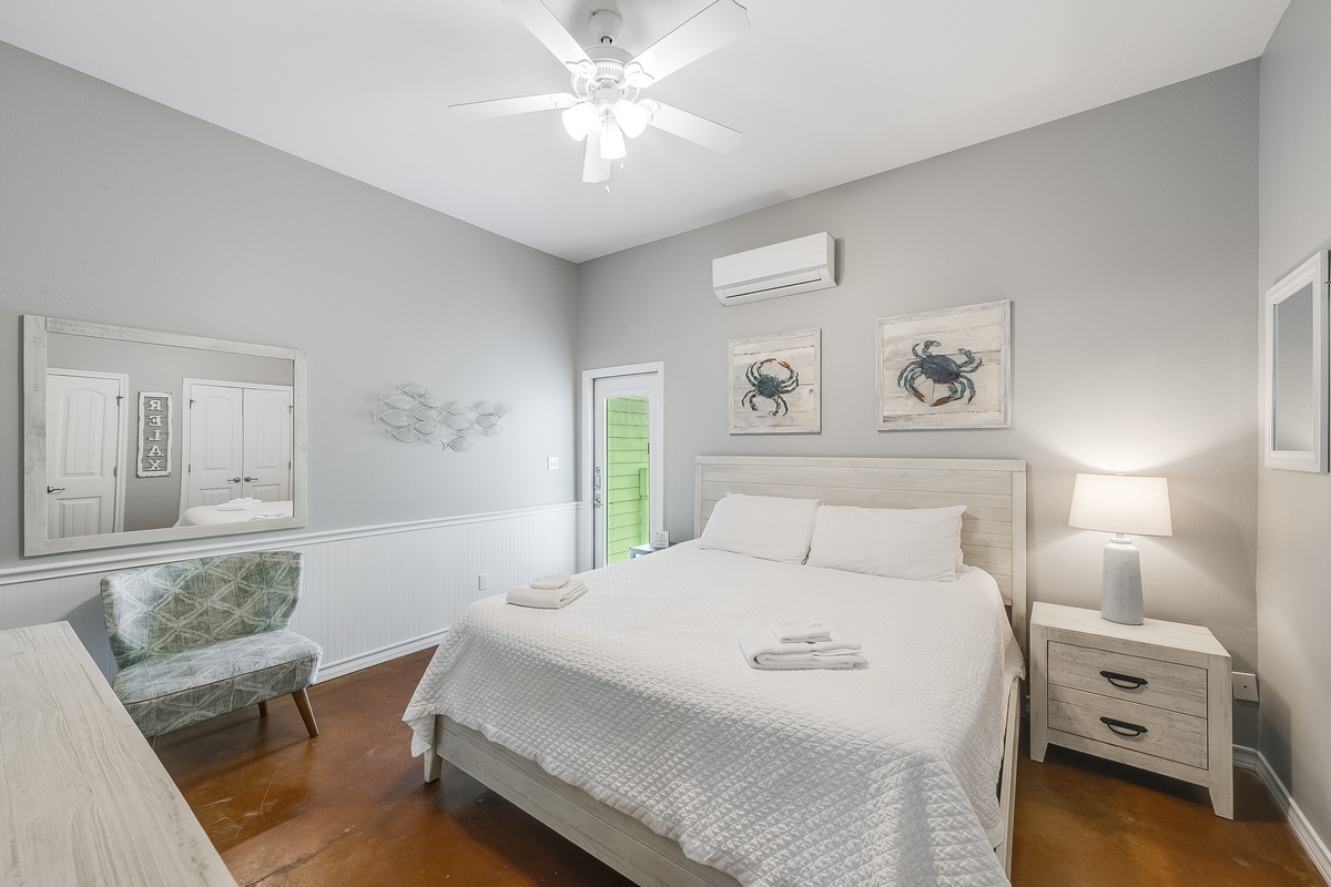 Sink into your coastal retreat with ocean-themed art and pristine linens awaiting your arrival in this serene bedroom.