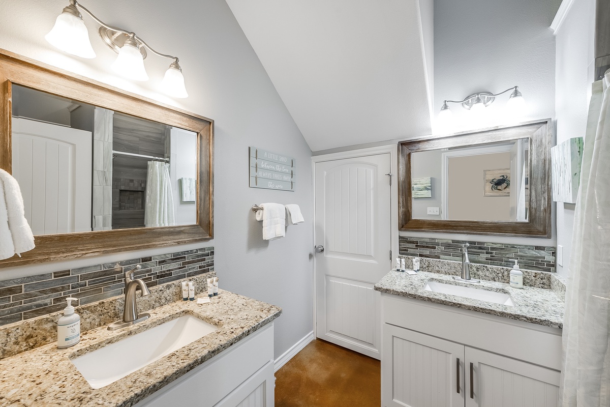 Start your day in this beautifully appointed bathroom with dual vanities, granite countertops, and elegant tile backsplash for your comfort.
