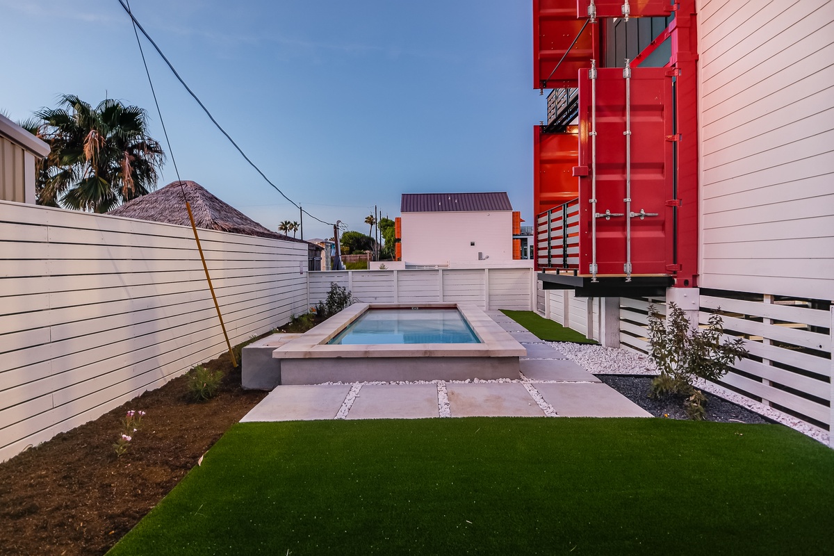Relax in your private oasis with a sleek modern pool surrounded by lush artificial grass and contemporary design.