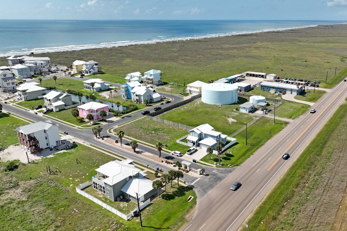 Coastal community with modern beach homes situated between ocean and grasslands, offering a serene seaside setting.