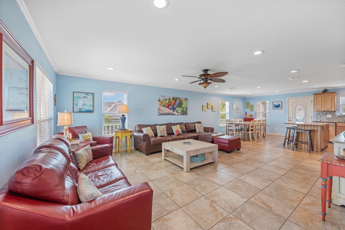 Relax in your spacious open-concept living area with comfortable leather seating, coastal decor, and a fully equipped kitchen for memorable gatherings.