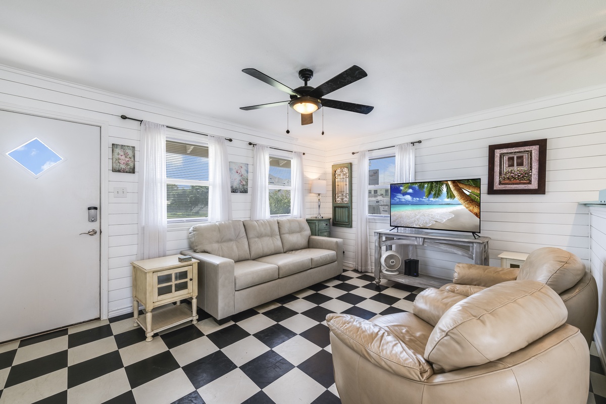 Your comfortable living room awaits with plush seating, a large TV for movie nights, and a ceiling fan to keep you cool. Relax on the sofas and unwind in this bright, welcoming space.