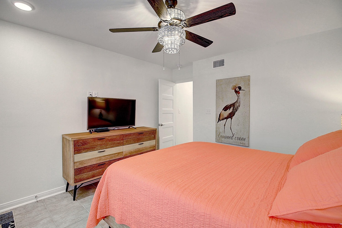 Relax in your bright bedroom with elegant touches like the crystal ceiling fan and charming coastal artwork.