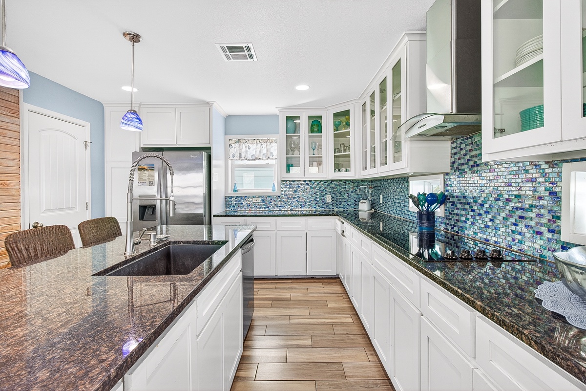 Your gourmet kitchen awaits with sparkling granite counters, ocean-inspired tile backsplash, and everything you need to create memorable meals together.