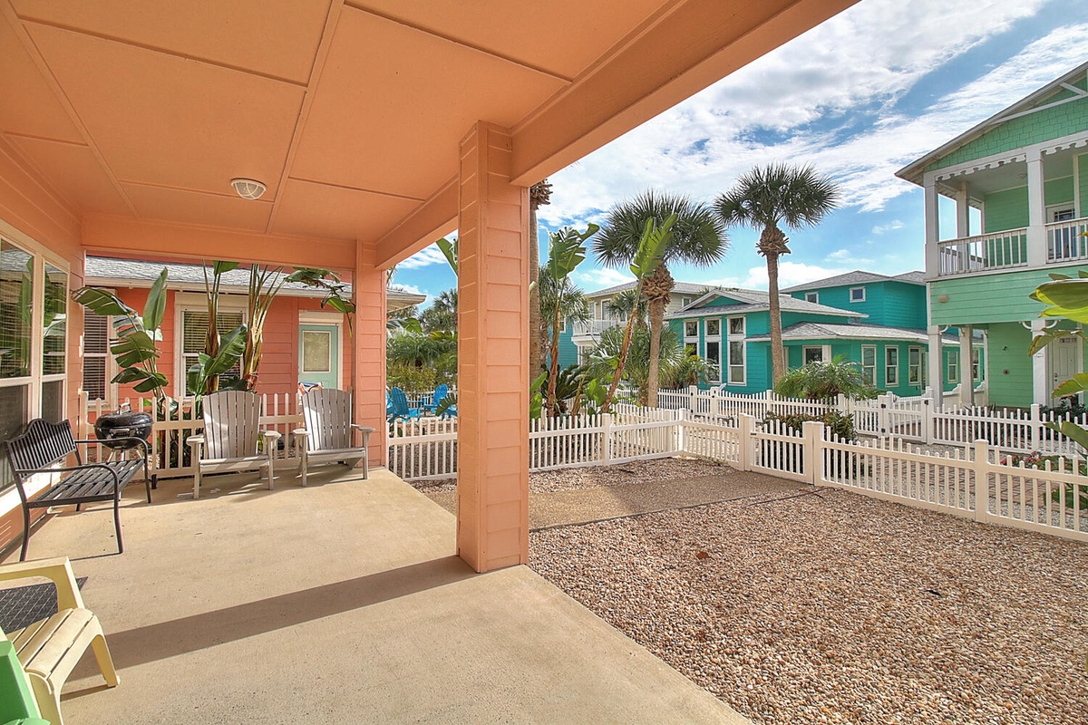 Relax on your private covered patio with comfortable seating, perfect for morning coffee while enjoying the tropical atmosphere and colorful neighborhood views.