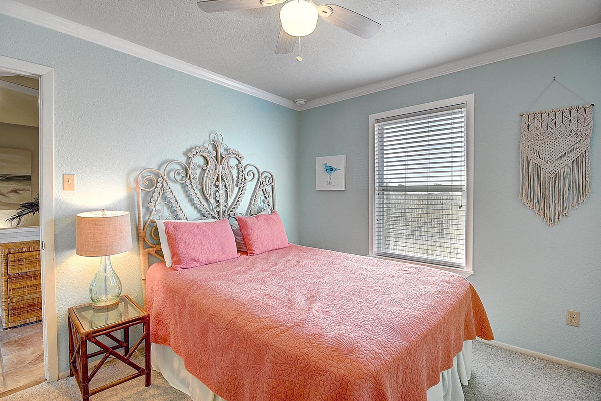 Drift off in this dreamy bedroom with ornate headboard, soft coral bedding, and gentle ceiling fan keeping you comfortable all night.