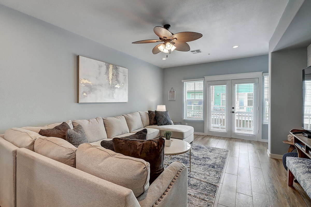 Sink into plush sectional seating where warm wood floors and soothing blue walls create your perfect retreat for relaxing evenings.