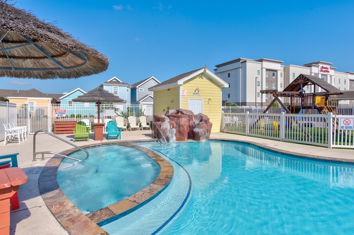 Splash into fun at this vibrant pool area featuring crystal-clear waters, a relaxing hot tub, and colorful beach huts creating a playful coastal vibe.