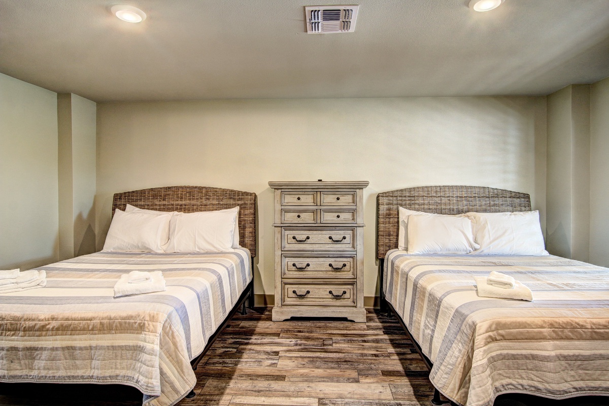 Your peaceful bedroom features two comfortable beds with coastal wicker headboards, perfect for sharing with family or friends.