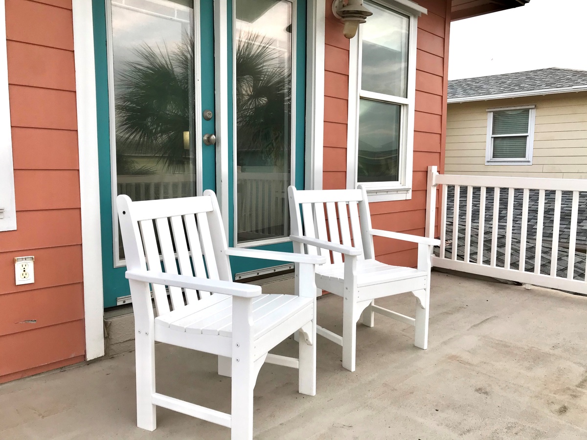 Settle into your private covered patio with comfortable white chairs, perfect for morning coffee or evening relaxation while enjoying the peaceful surroundings.
