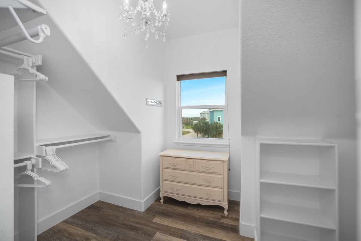 Your cozy bedroom features elegant white built-ins, a crystal chandelier, and peaceful views through the bright window.