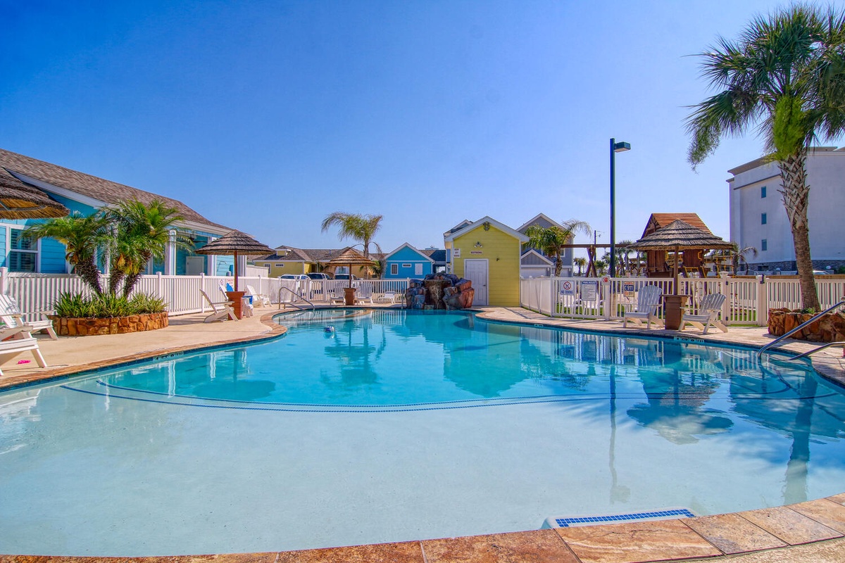 Sparkling pool surrounded by colorful beach cottages and swaying palms creates your perfect tropical getaway.