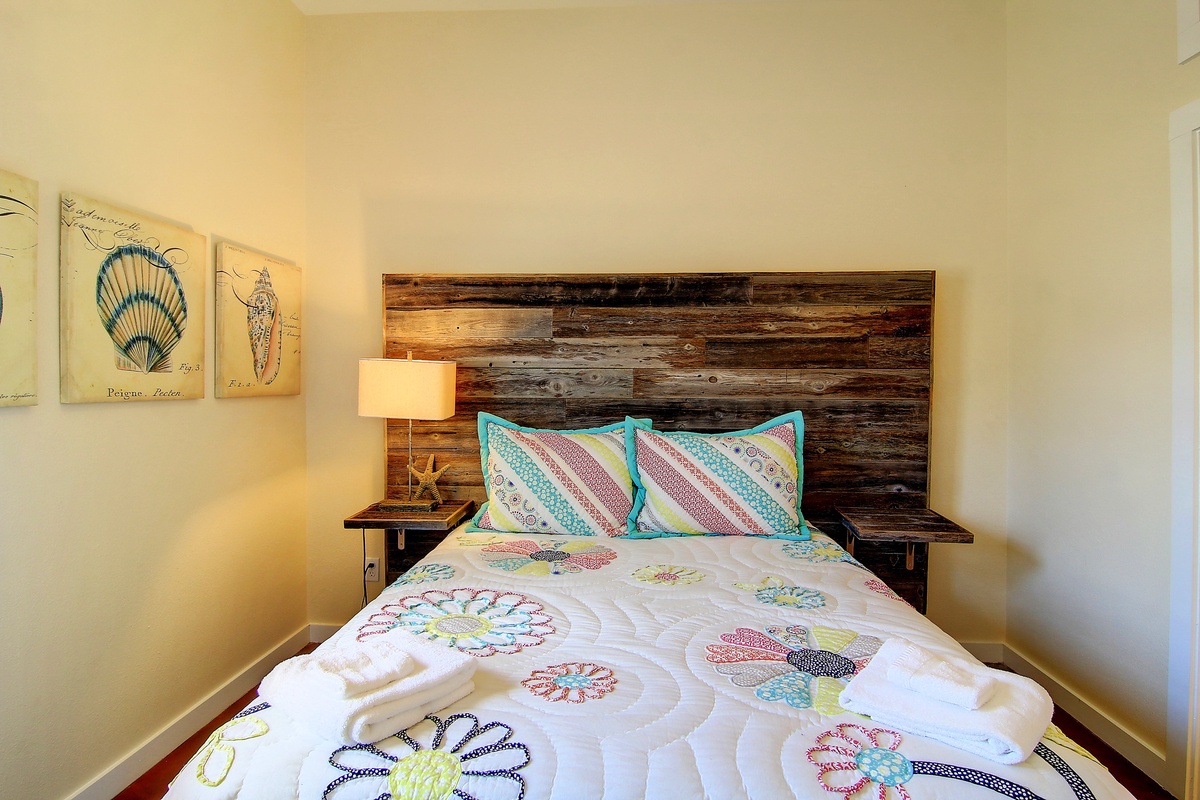 Drift off in your cozy coastal retreat, where rustic wood meets whimsical ocean-themed linens and charming seaside artwork.