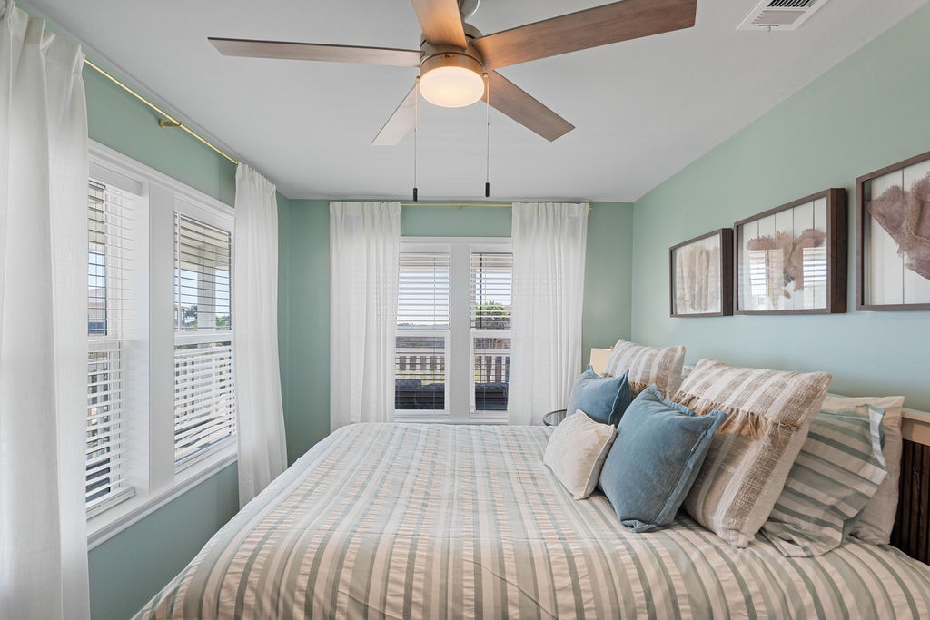 Wake up in this serene bedroom with soothing seafoam walls, crisp linens, and gentle breezes from your ceiling fan.