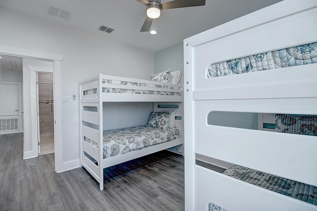 Your kids will love this cozy bunk room with soft coastal bedding and a ceiling fan for comfort.