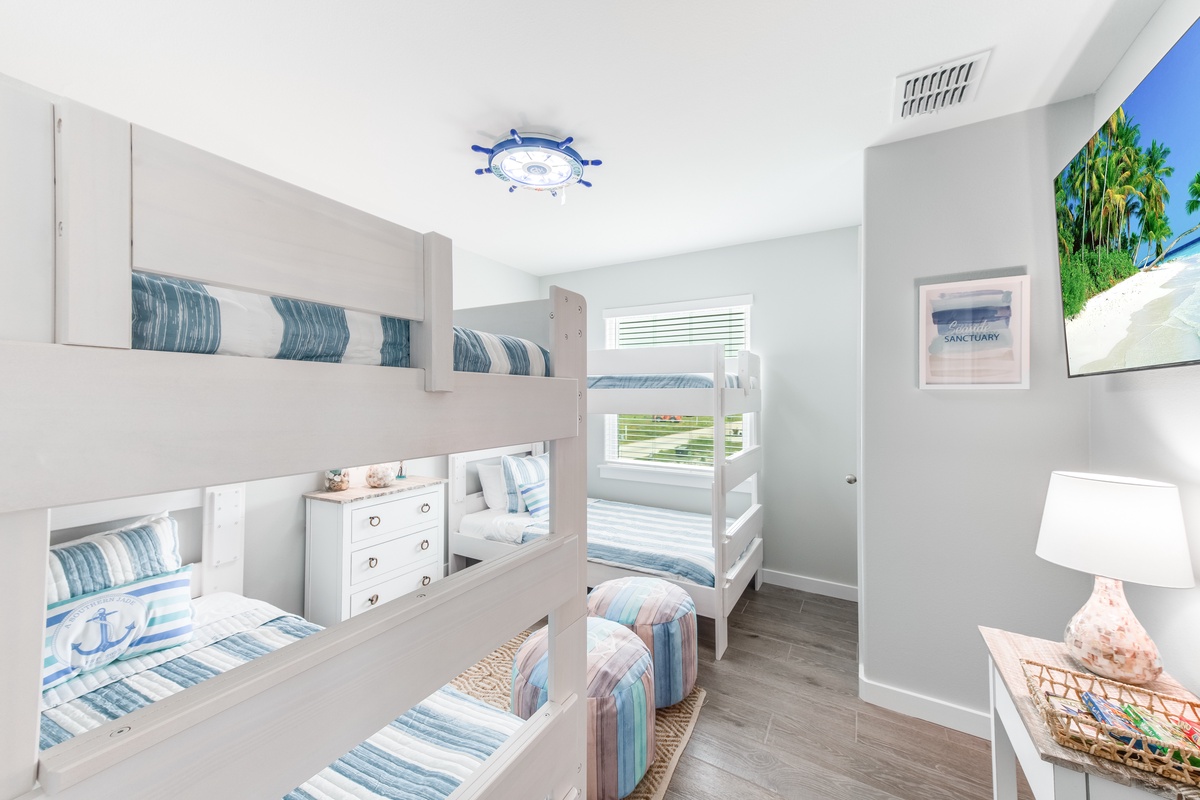 Your kids will love this nautical-themed bunk room with cozy striped bedding and charming ship's wheel ceiling fan.