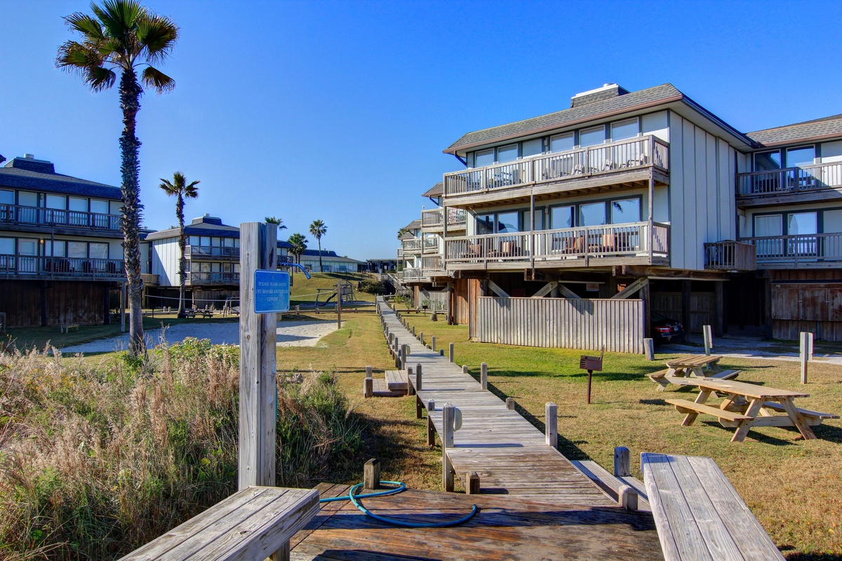 Charming coastal property featuring wooden boardwalk access to waterfront accommodations with private balconies and scenic palm-lined grounds.