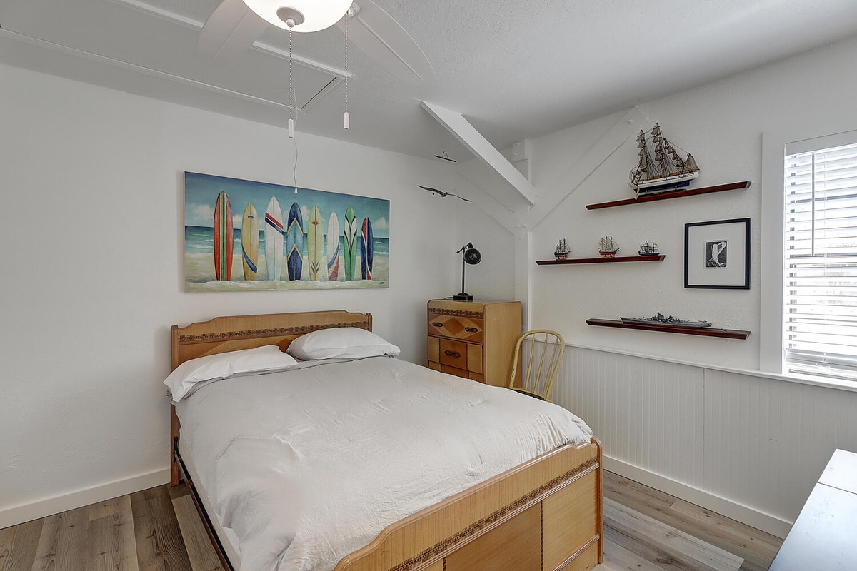 Drift off in this charming nautical bedroom where colorful surfboard art and ship models create coastal dreams.