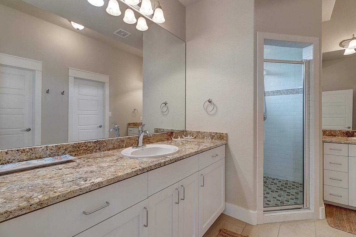 Step into your luxurious bathroom with granite countertops, bright vanity lighting, and a spacious tiled shower for ultimate comfort.