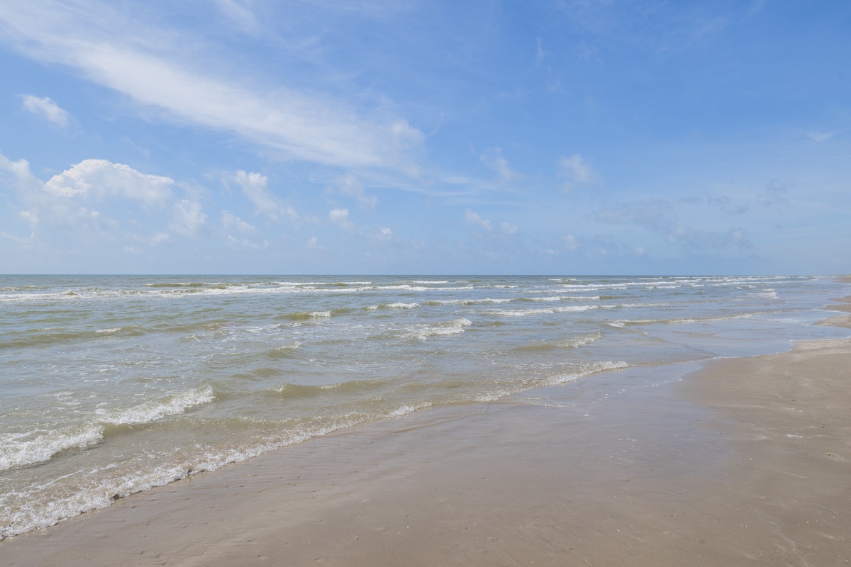 A beautiful sandy beach stretches along calm turquoise waters under a clear blue sky, offering an ideal coastal escape near the property.