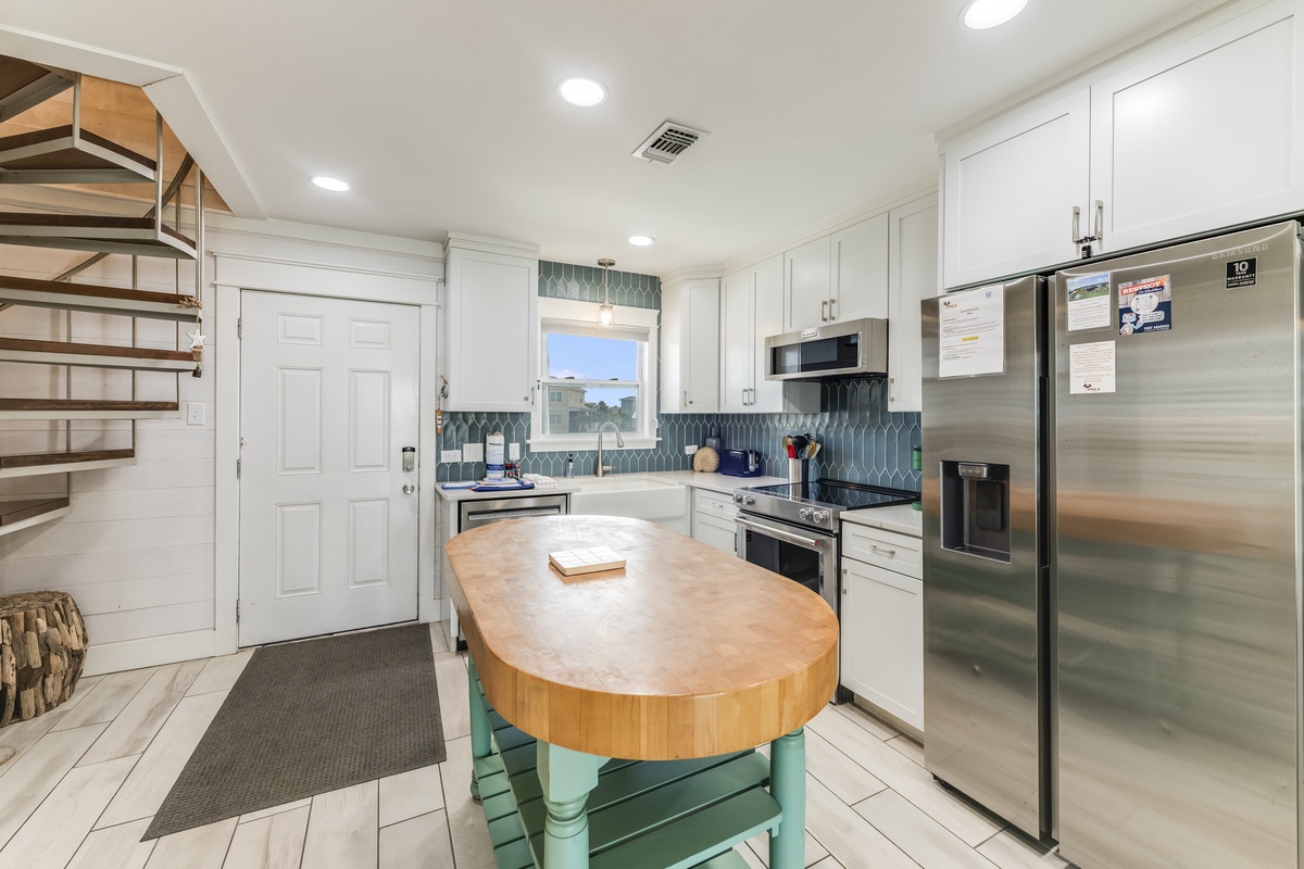 Your fully-equipped kitchen invites relaxed meal prep with modern stainless appliances, charming coastal-inspired backsplash, and a butcher-block island where you can gather and create.