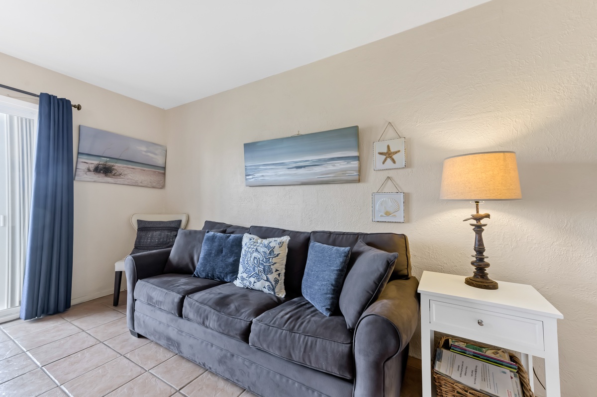 Settle into your cozy living space featuring plush seating, coastal artwork, and warm lighting for perfect relaxation.