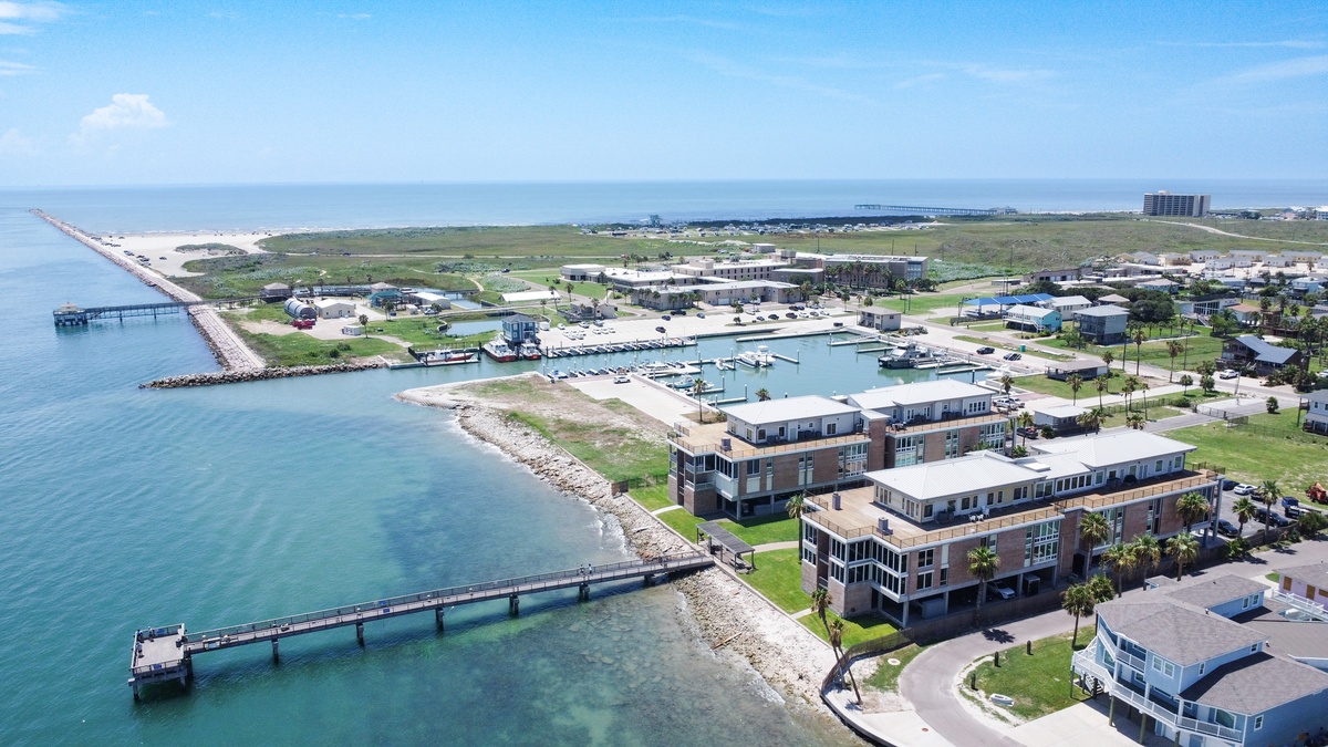 Stunning aerial view of this coastal waterfront community featuring marina access, pristine beaches, and modern accommodations overlooking turquoise waters.