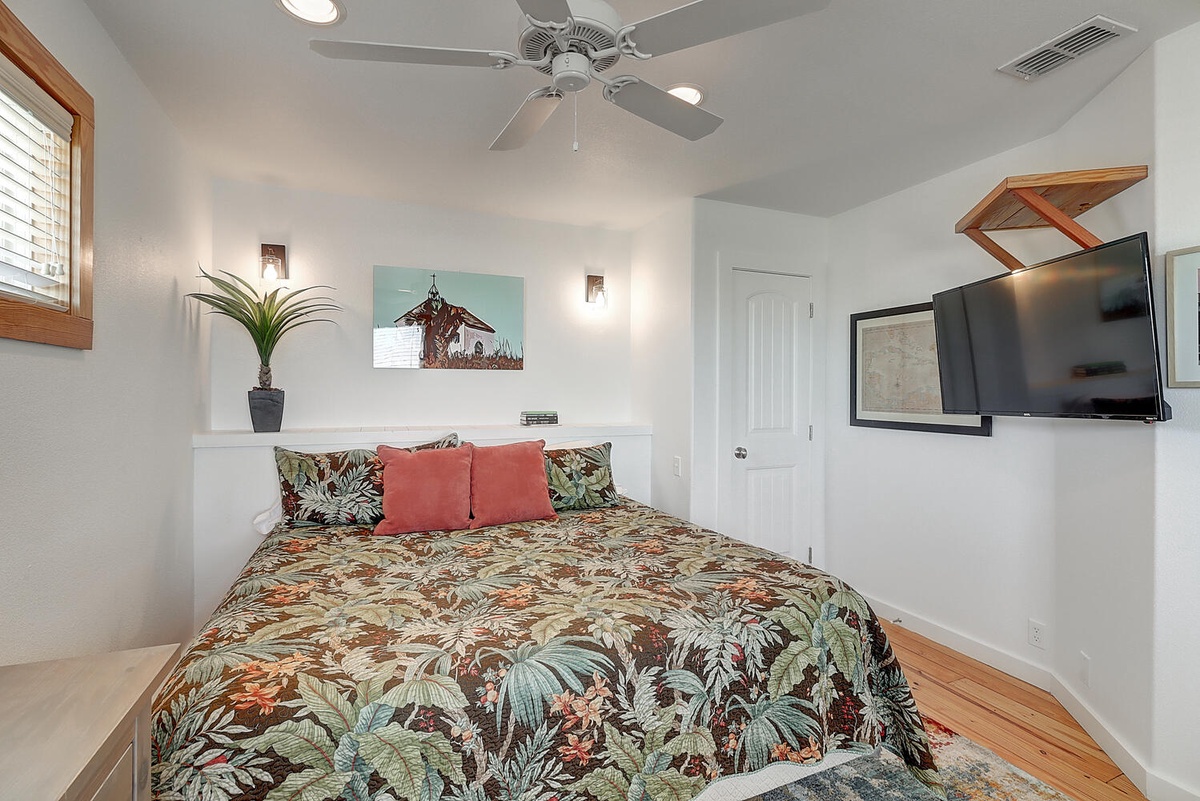 Drift off in your tropical bedroom sanctuary, complete with island-inspired linens, ceiling fan, and mounted TV for cozy evenings.