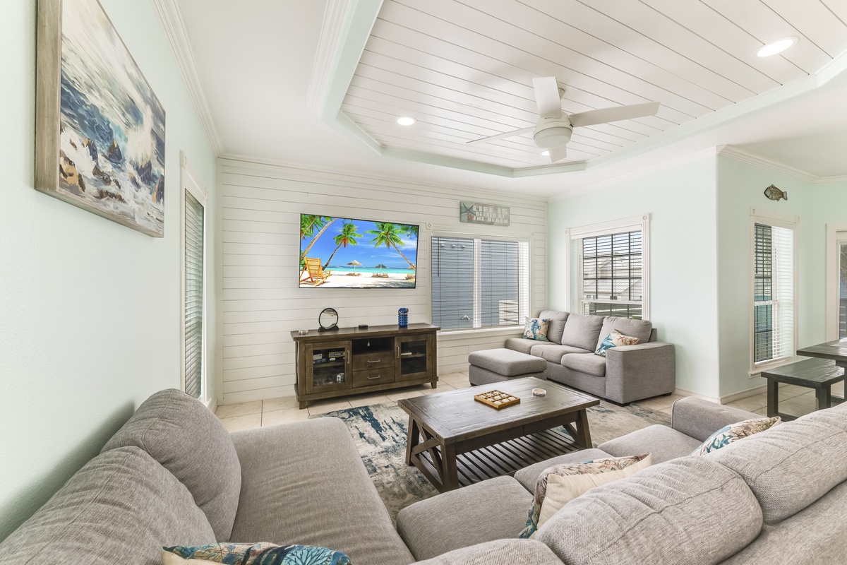Relax in your bright coastal living room with plush sectional seating, smart TV, and charming shiplap ceiling.