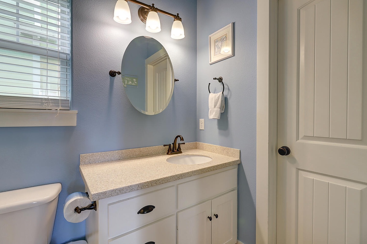 Refresh in your beautifully appointed bathroom featuring soft blue walls, elegant vanity lighting, and thoughtful touches like fresh towels.
