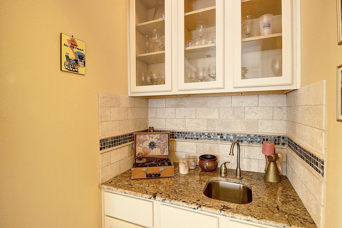 Your charming wet bar features granite counters and glass-front cabinets, perfect for evening cocktails in your elegant retreat.