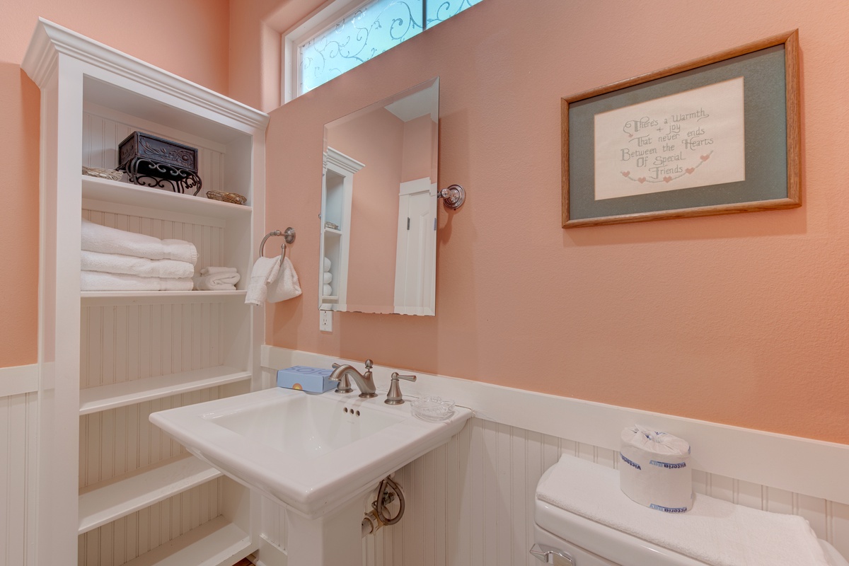 Your private bathroom features warm peachy walls, built-in storage with fluffy towels, and charming vintage details that make every morning feel special.