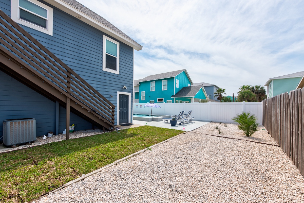 A charming coastal backyard with pool and deck chairs where you'll unwind after beach days in this colorful neighborhood setting.
