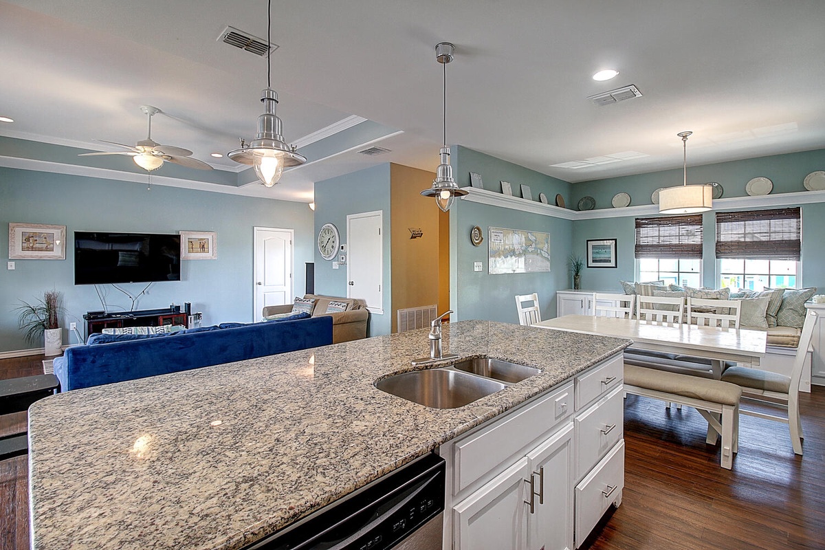 Your open-concept haven seamlessly blends kitchen, dining, and living spaces with coastal blue walls and granite countertops for effortless entertaining.