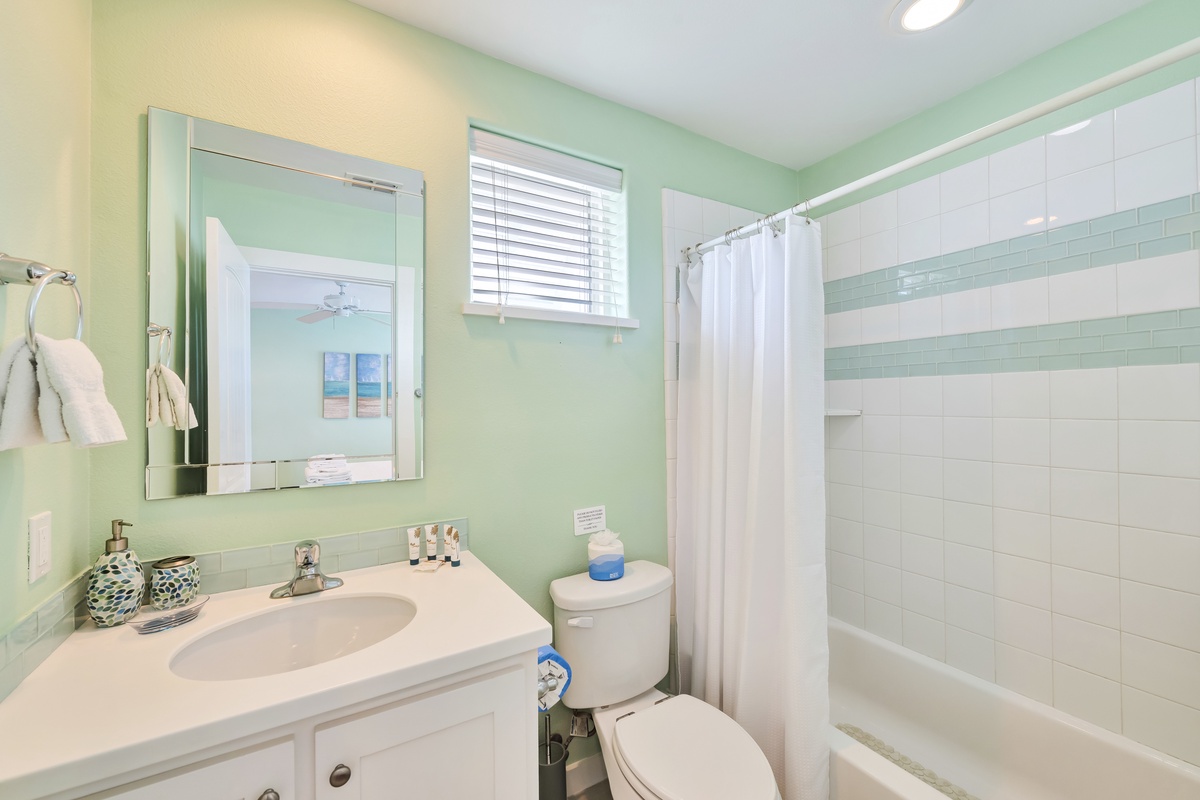 Refresh in your private bathroom with soothing mint green walls, modern fixtures, and a relaxing tub-shower combo for unwinding after beach days.
