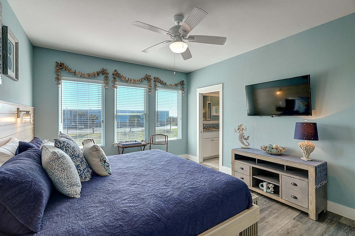 Wake up to stunning water views in this coastal bedroom with cozy navy bedding and soothing sea-inspired decor.