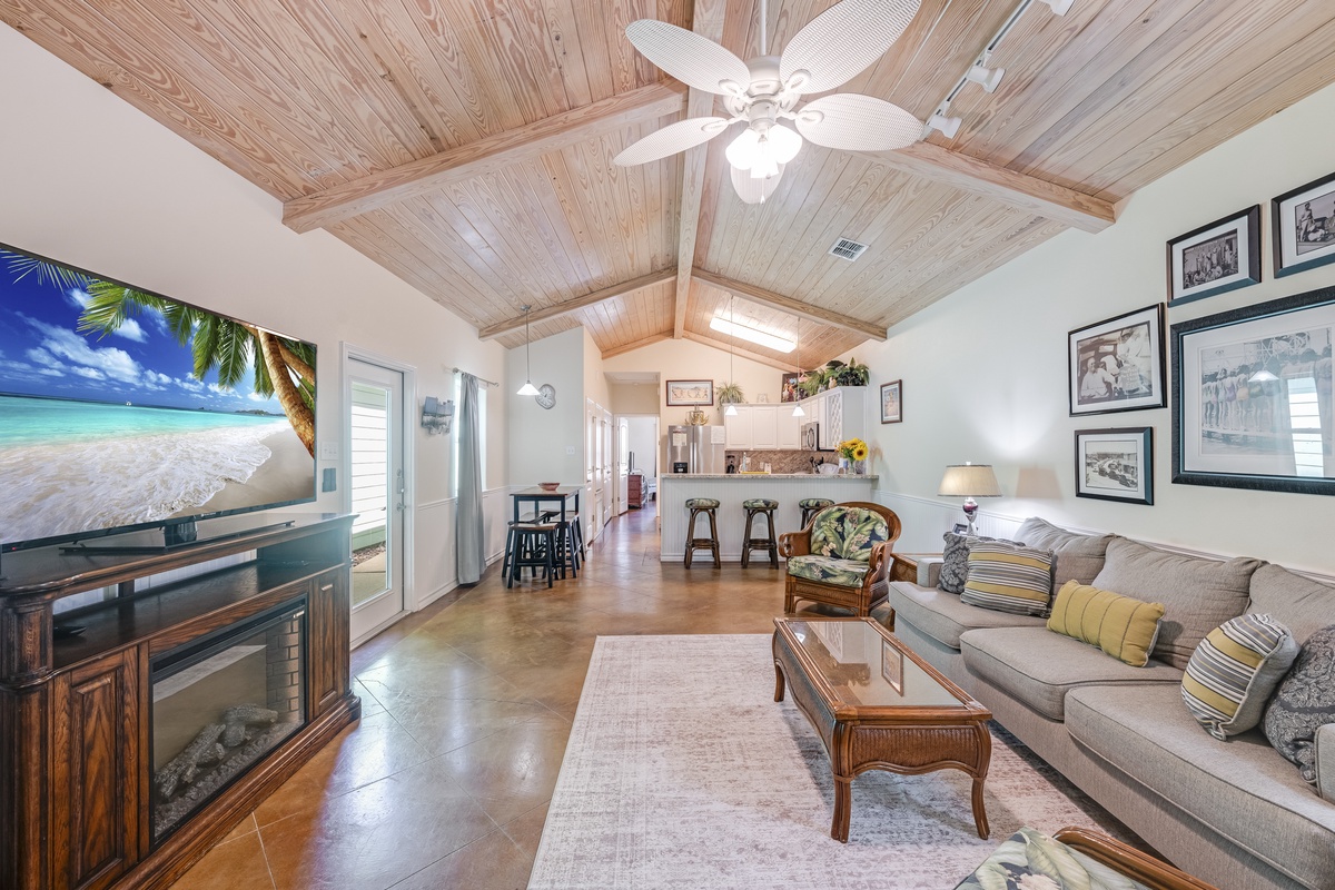 Relax in your open-concept living space featuring soaring wood-beamed ceilings, cozy seating, and tropical touches that create the perfect island retreat atmosphere.