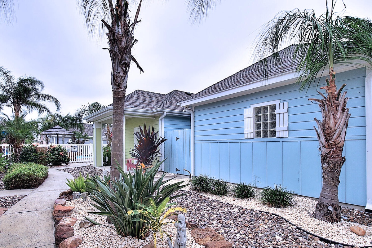 Charming coastal cottage with tropical landscaping and palm trees creates a perfect island getaway atmosphere.