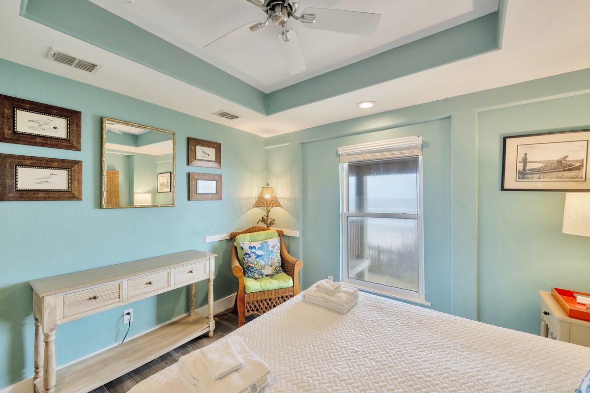 Relax in your coastal bedroom with soothing turquoise walls, wicker seating, and thoughtful decor that creates a peaceful seaside retreat.