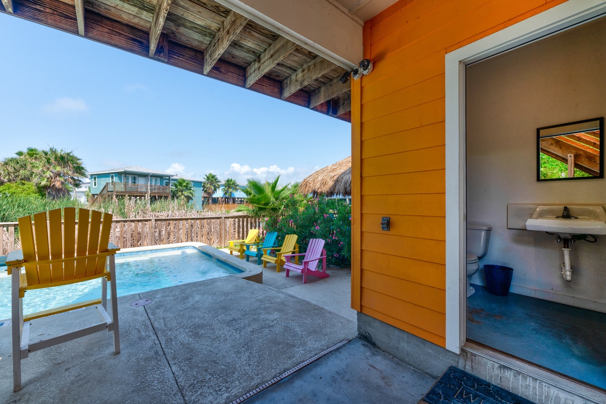 Your private pool deck awaits with colorful Adirondack chairs and tropical views, just steps from your cozy bathroom retreat.