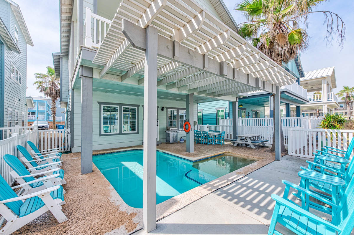 Your private pool awaits with turquoise chairs and a shaded pergola for perfect poolside relaxation.